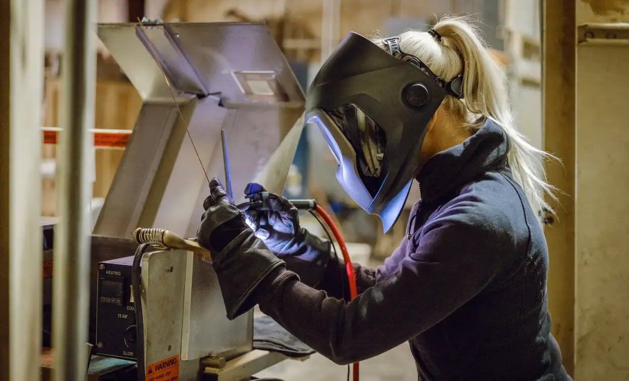 Kvinnlig arbetare jobbar på industriföretag med skyddsvisir och tänker på soliditet
